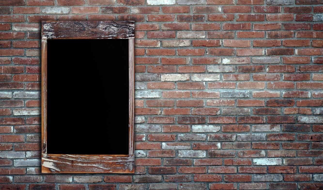 A wall of brick with a wooden framed window.